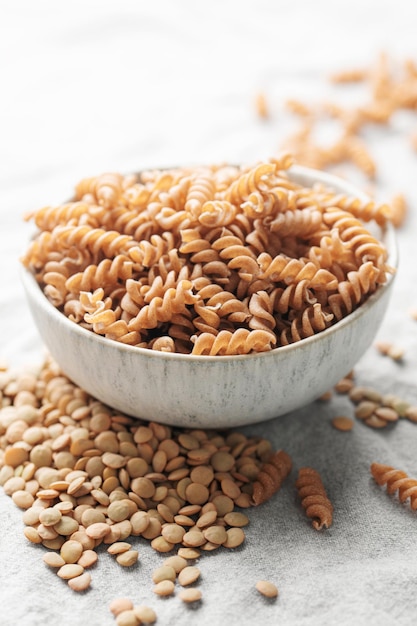 Macarrão fusilli de lentilha verde sobre um fundo têxtil cinza