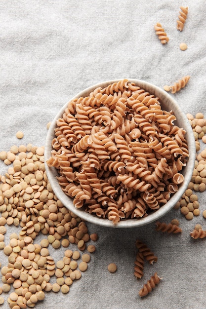 Macarrão fusilli de lentilha verde sobre um fundo têxtil cinza