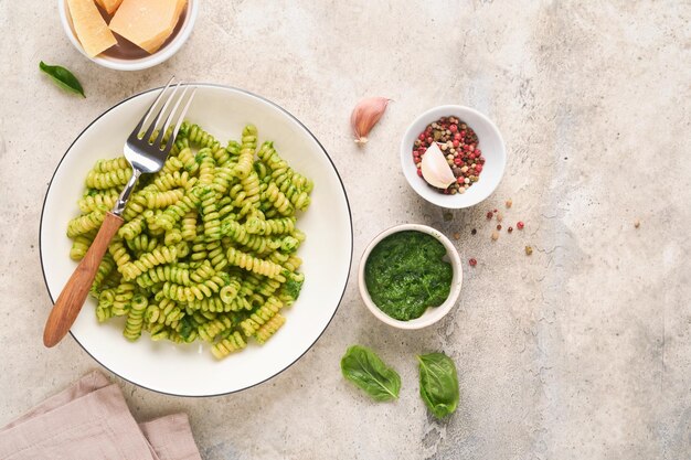 Macarrão fusilli italiano com pesto macarrão fusilli com pesto de manjericão e ervas queijo parmesão manjericão e alho na chapa branca no fundo da bancada de pedra cinza vista superior copiar espaço mock up