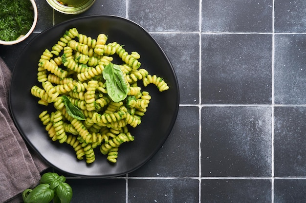 Macarrão Fusilli italiano com Pesto Macarrão Fusilli com pesto de manjericão e ervas queijo parmesão manjericão e alho na chapa preta no fundo da bancada de pedra preta Vista superior Copiar espaço Mock up