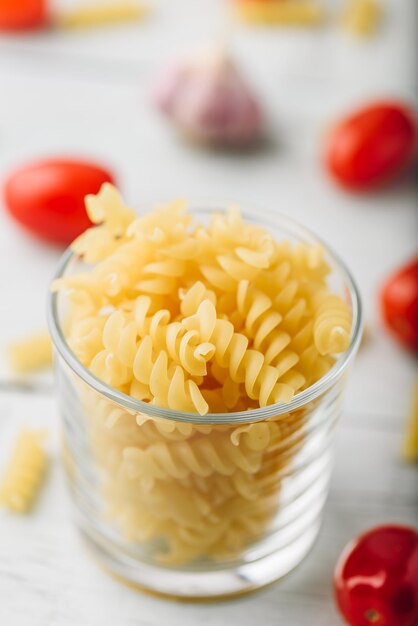 Foto macarrão fusilli italiano em tigela de vidro com tomate cereja e alho