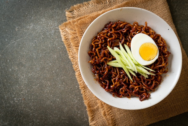 Macarrão instantâneo coreano com molho de feijão preto coberto com pepino e ovo cozido (jajangmyeon ou jjajangmyeon) - estilo de comida coreana