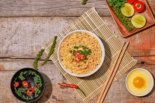 Macarrão instantâneo em uma tigela com vegetais na mesa de madeira.