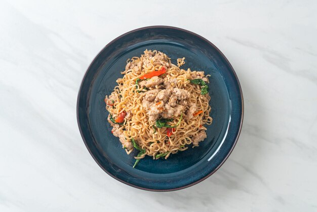 macarrão instantâneo frito caseiro com manjericão tailandês e carne de porco picada - comida tailandesa