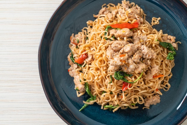 macarrão instantâneo frito caseiro com manjericão tailandês e carne de porco picada - comida tailandesa