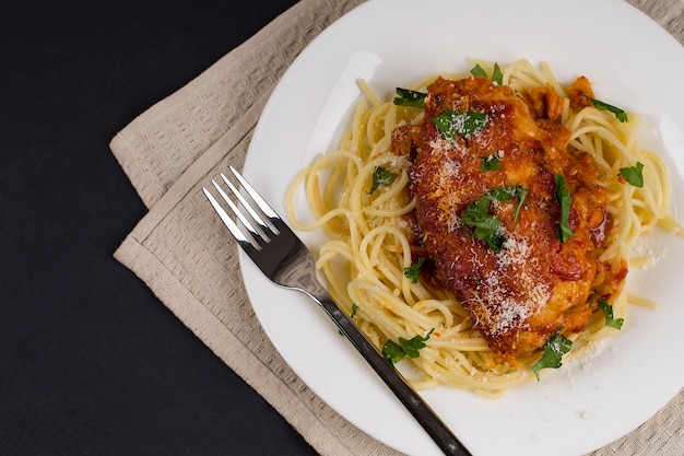 Macarrão italiano de frango à parmegiana com ervas e molho de tomate. Sobre um fundo cinza. Vista do topo.