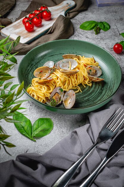 Macarrão italiano tradicional de frutos do mar com marisco Spaghetti alle Vongole em um prato sobre uma mesa de pedra cinza. Cardápio do restaurante