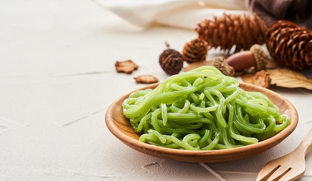 macarrão konjac verde na placa de madeira no fundo da mesa branca