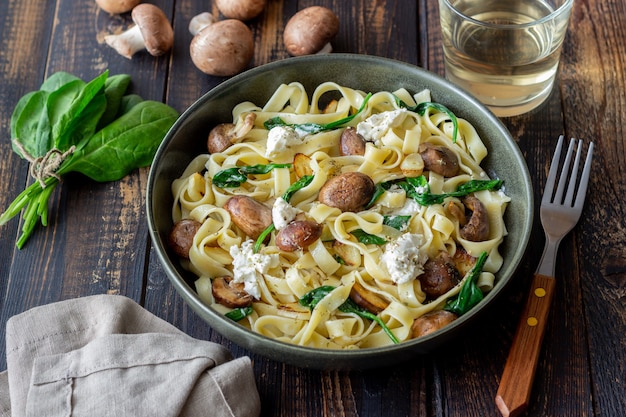 Macarrão linguine com cogumelos, queijo branco, espinafre e alho. Alimentação saudável. Comida vegetariana. Dieta.