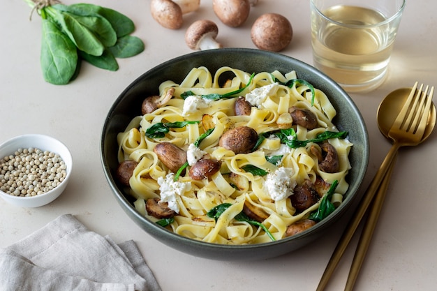 Macarrão linguine com cogumelos, queijo branco, espinafre e alho. Alimentação saudável. Comida vegetariana. Dieta.