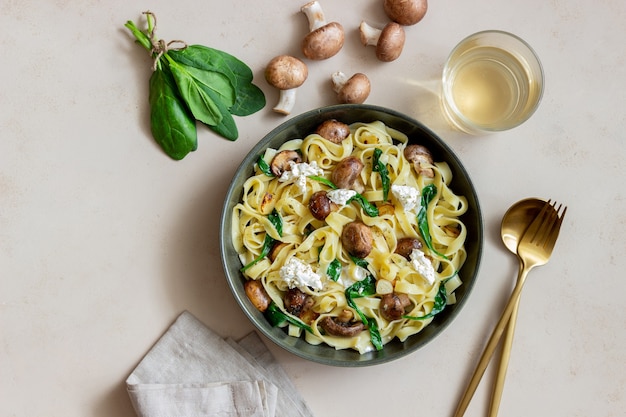 Macarrão linguine com cogumelos, queijo branco, espinafre e alho. Alimentação saudável. Comida vegetariana. Dieta.