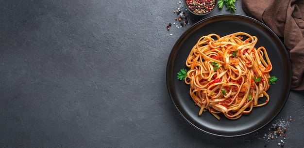 Macarrão linguini com molho de tomate e salsa em um fundo escuro