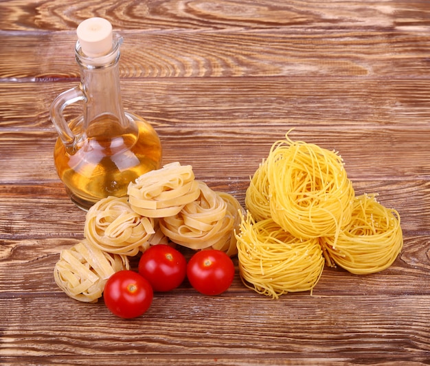 Foto macarrão na parede de madeira com tomate, pimenta de alface, azeite e pimenta. vista superior