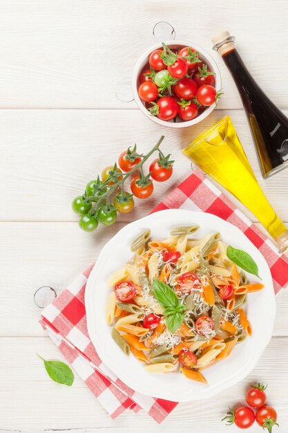 Foto macarrão penne colorido com tomate e manjericão