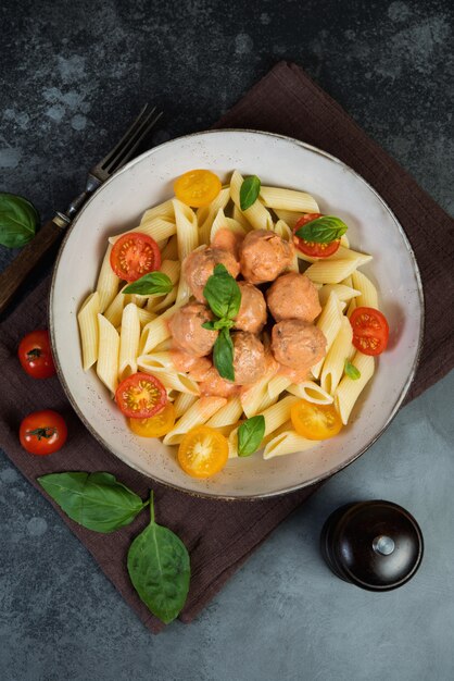 Foto macarrão penne com almôndegas de tomate e molho em um fundo escuro