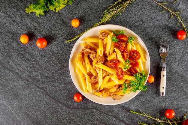 Macarrão penne com carne e tomate cereja em tigela branca Vista superior