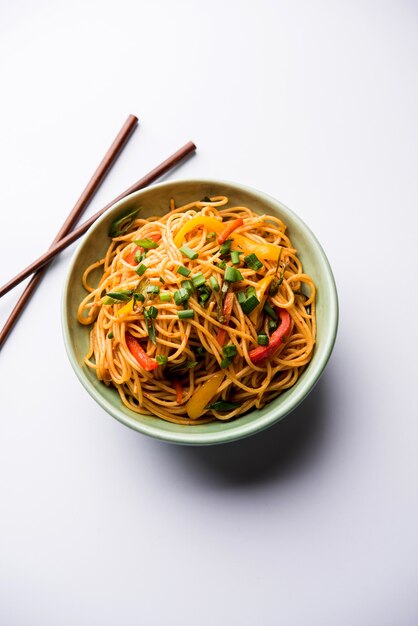 Macarrão schezwan ou macarrão hakka de vegetais ou chow mein são receitas indo-chinesas populares, servidas em uma tigela ou prato com pauzinhos de madeira