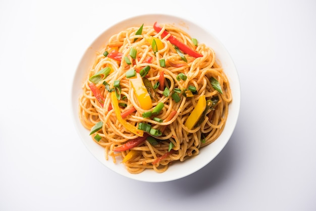 Macarrão Schezwan ou macarrão Hakka vegetal ou chow mein são receitas indo-chinesas populares, servidas em uma tigela ou prato com pauzinhos de madeira. foco seletivo