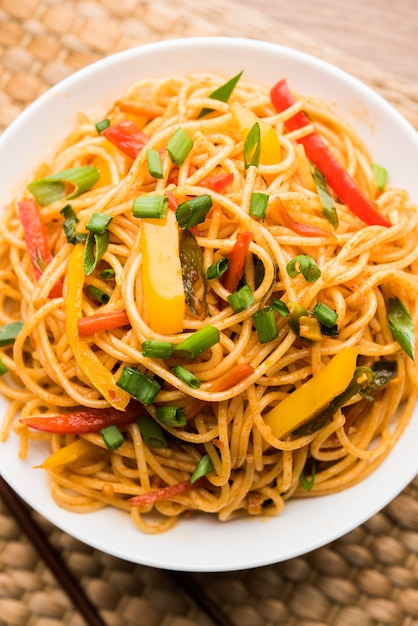 Macarrão schezwan ou macarrão hakka vegetal ou chow mein são receitas indo-chinesas populares, servidas em uma tigela ou prato com pauzinhos de madeira. foco seletivo