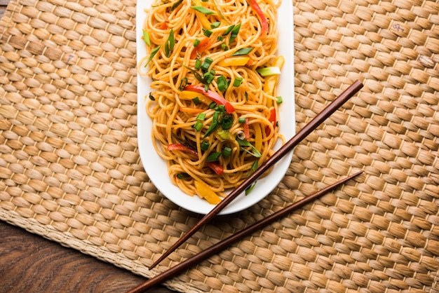 Macarrão Schezwan ou macarrão Hakka vegetal ou chow mein são receitas indo-chinesas populares, servidas em uma tigela ou prato com pauzinhos de madeira. foco seletivo