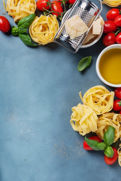 Macarrão seco, tomate cereja e ingredientes na mesa de concreto