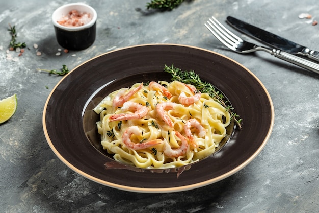 Macarrão Tagliatelle com camarão grelhado, molho bechamel e tomilho, macarrão fettuccine. Comida italiana. Fundo de receita de comida. Fechar-se.