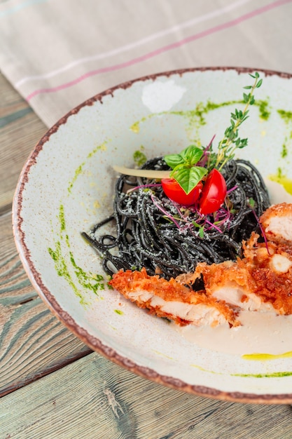 Macarrão tagliolini preto fresco com frango em ervas na rúcula e tomate