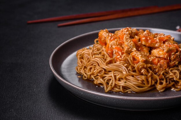 Macarrão tailandês e prato de frango em um fundo preto de concreto com pauzinhos chineses e espaço de cópia