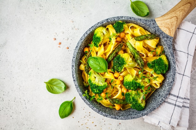 Macarrão vegetariano com brócolis, aspargos e grão de bico na panela