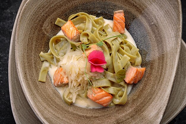 Macarrão verde com salmão e queijo no escuro