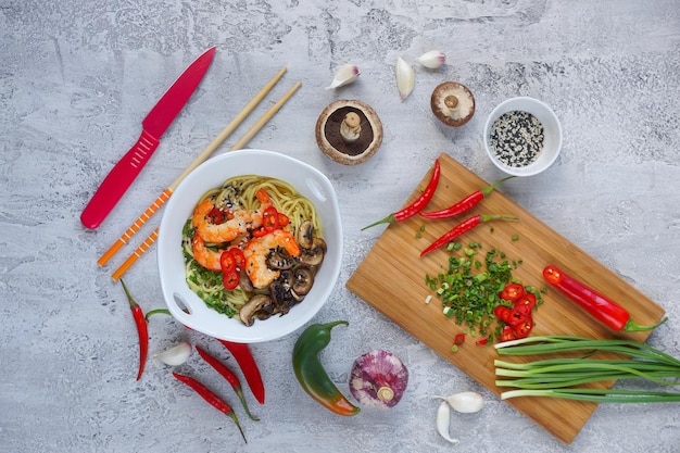 Macarrão wok asiático quente com camarões e cogumelos, Ramen, fundo cinza, vista superior