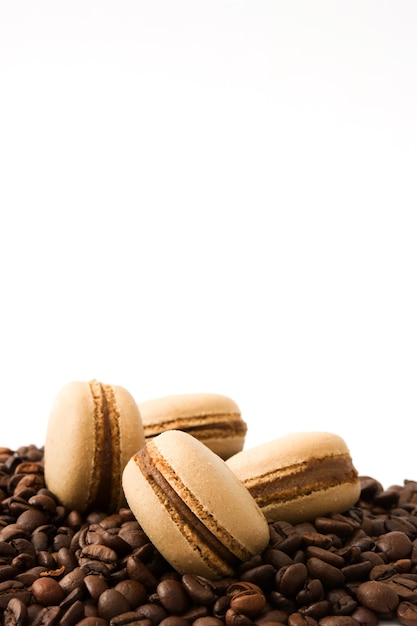 Macarrones de café y granos de café aislado sobre fondo blanco.