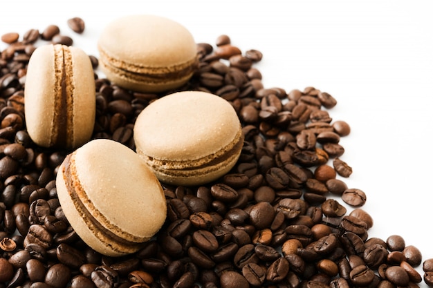 Macarrones de café y granos de café aislado sobre fondo blanco.