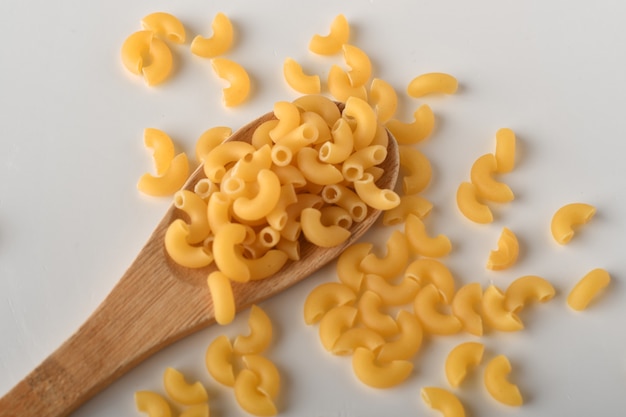 Macarrones de codo sin cocer sobre un fondo blanco.