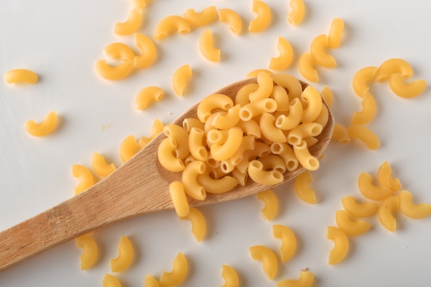 Macarrones de codo sin cocer sobre un fondo blanco.