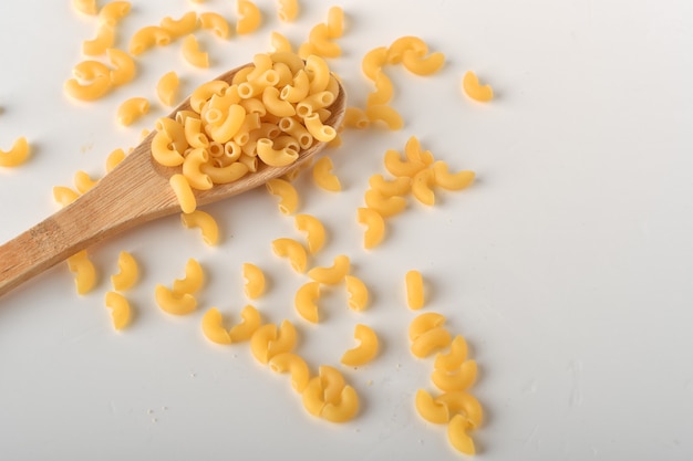 Macarrones de codo sin cocer sobre un fondo blanco.