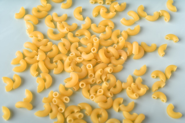 Macarrones de codo sin cocer sobre un fondo blanco.