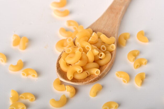 Macarrones de codo crudos sobre un fondo blanco.