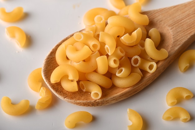 Macarrones de codo crudos sobre un fondo blanco.