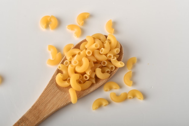 Macarrones de codo crudos sobre un fondo blanco.