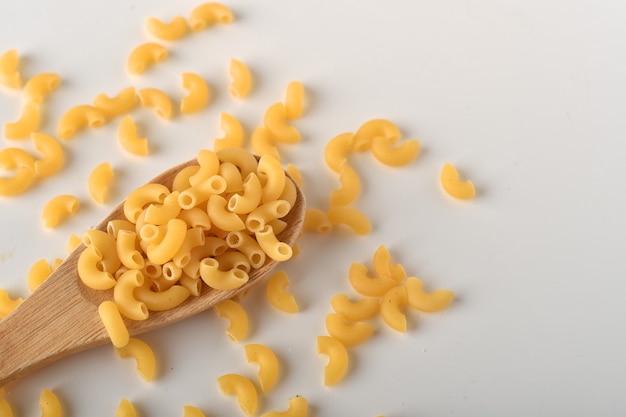 Macarrones de codo crudos sobre un fondo blanco.