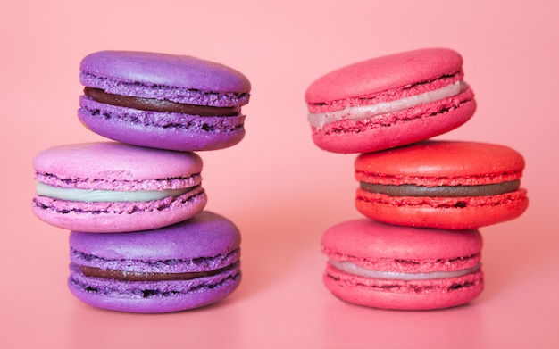 Macarrones de color rosa y violeta en una pila en un primer plano de fondo de coral de moda