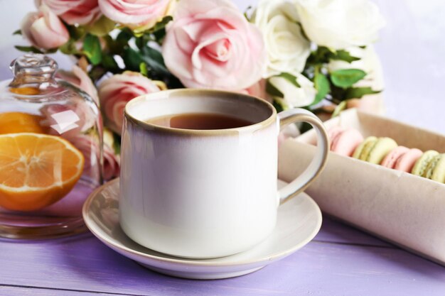 Macarrones coloridos con taza de té sobre fondo de madera