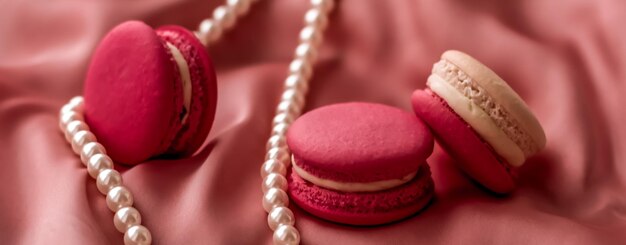 Macarrones dulces y joyas de perlas sobre fondo de seda joyería chic parisina Comida de postre francés y macaron de pastel para regalo de vacaciones de la marca de confitería de lujo