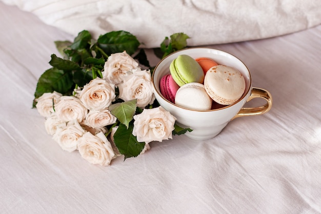 Macarrones dulces en taza y rosas blancas