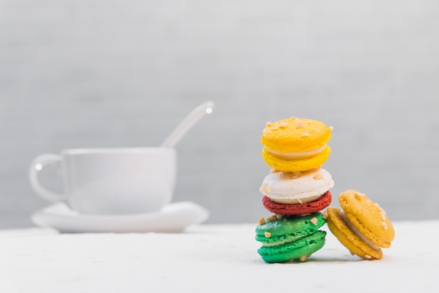 Macarrones franceses coloridos con la taza de café en el fondo blanco