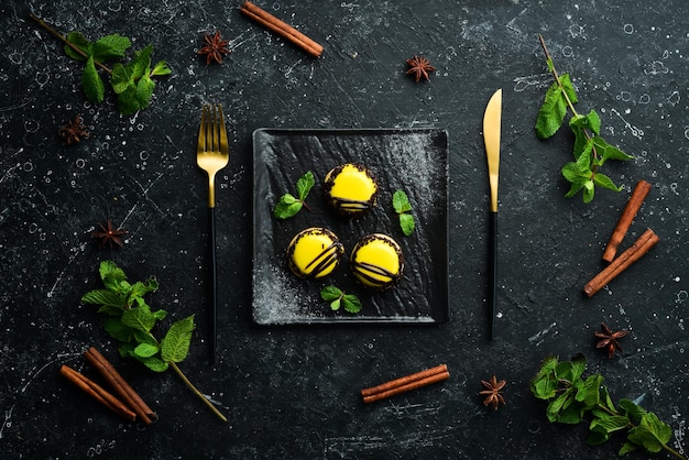 Macarrones de postres de mango amarillo en un plato negro con menta Vista superior Estilo rústico