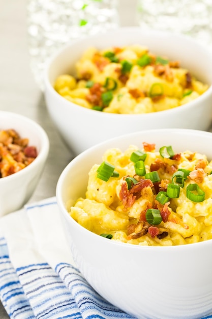 Macarrones con queso aderezado con trocitos de tocino y cebollino.