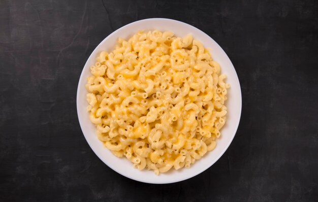 Macarrones con queso en un plato blanco sobre un fondo negro