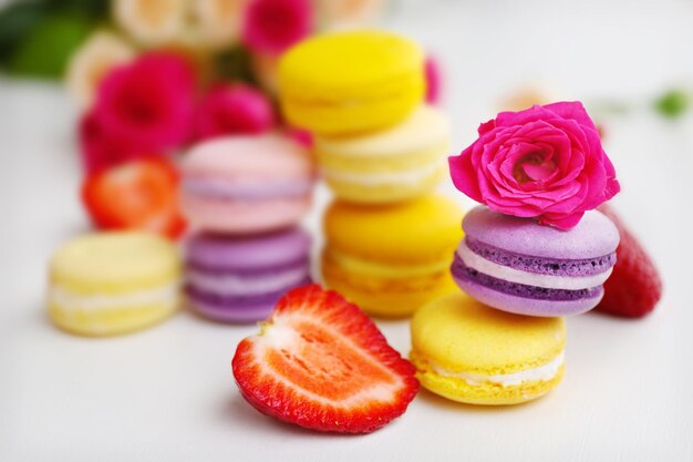 Macarrones con rosas y fresas sobre fondo blanco.